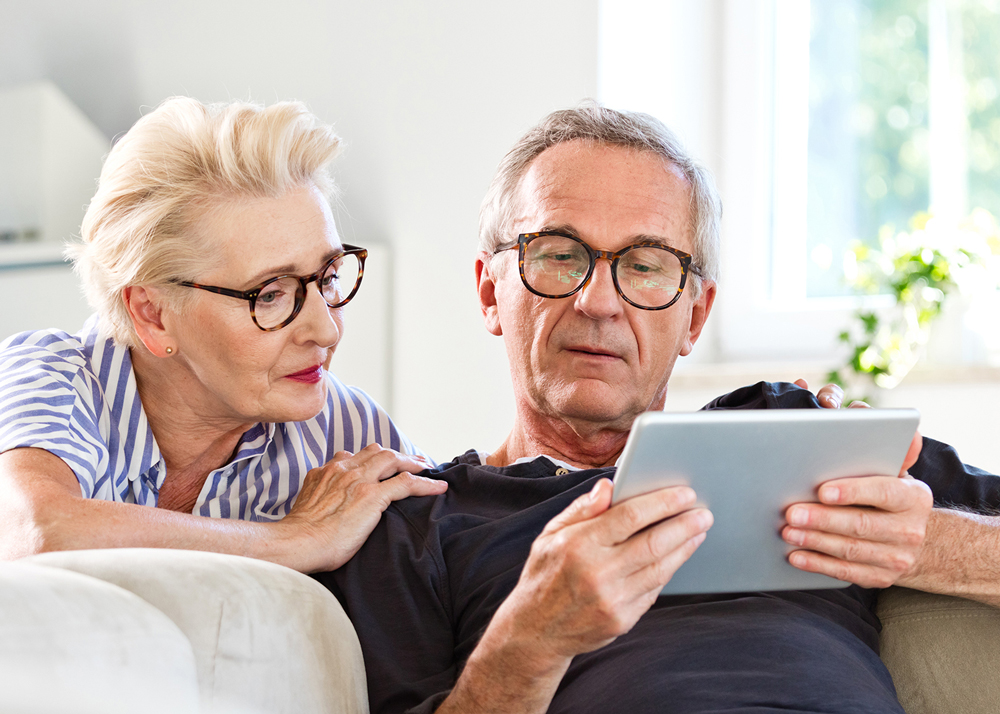 Elderly couple with glasses reading from a tablet