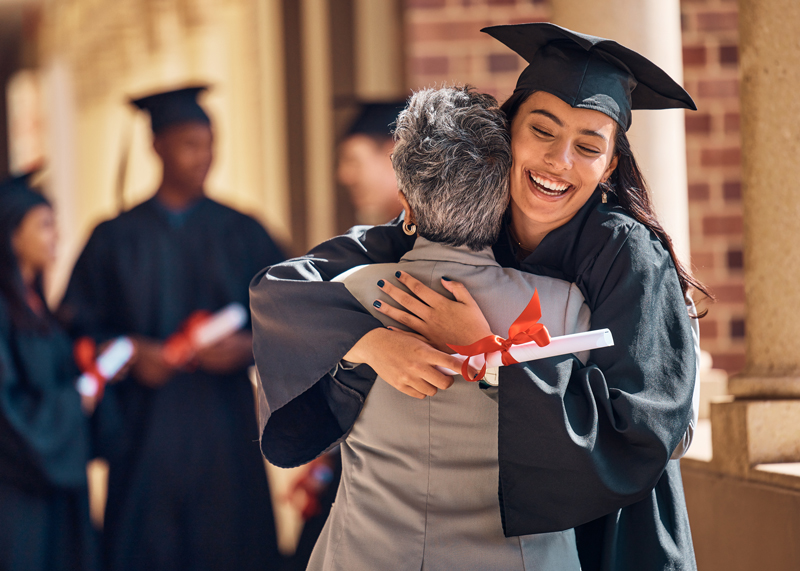 College graduate with diploma hugging their parent