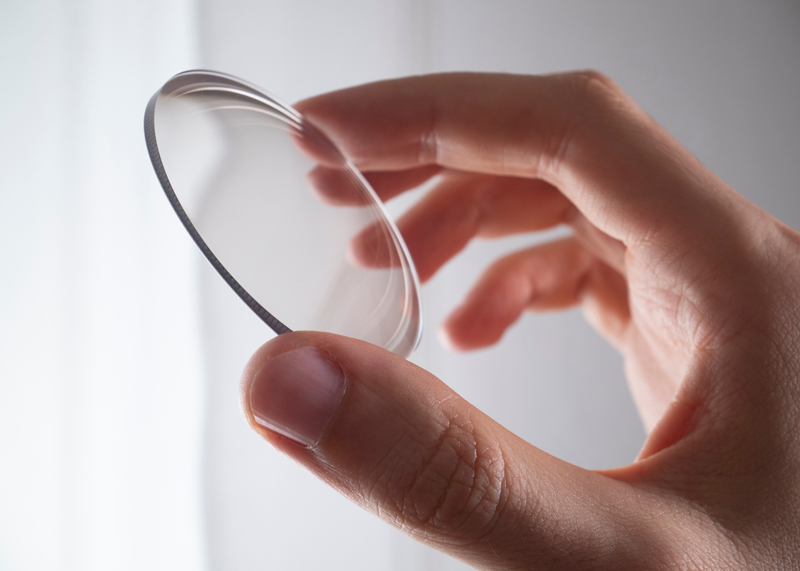 Hand holding a new eyeglass lens