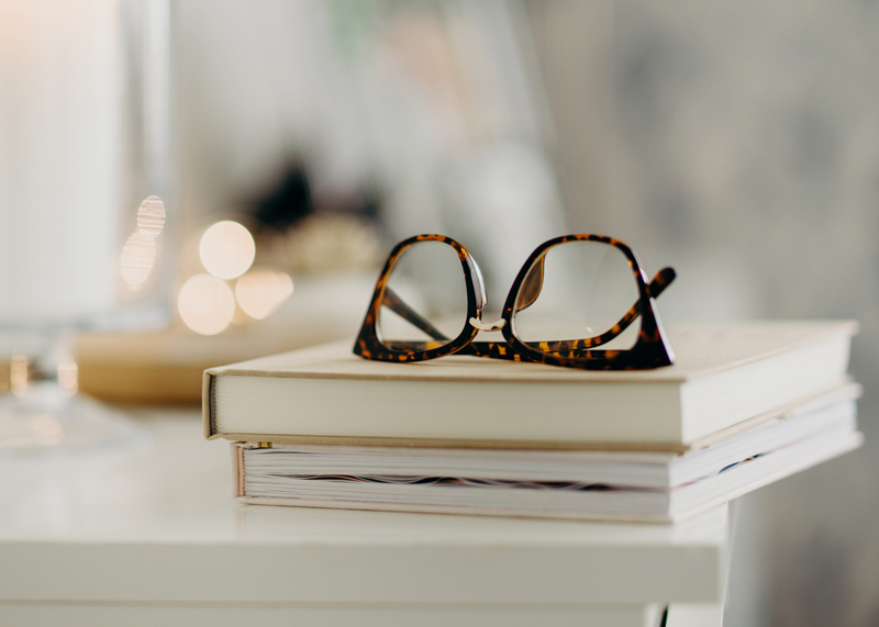 Pair of non-prescription reading glasses atop of a stack of books